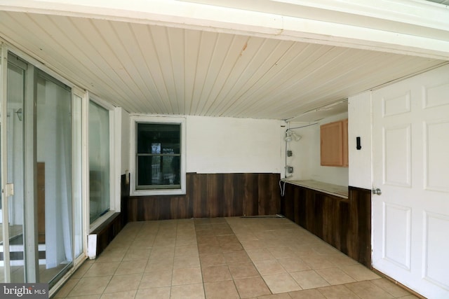 spare room featuring light tile patterned flooring, wood ceiling, a wainscoted wall, and wood walls