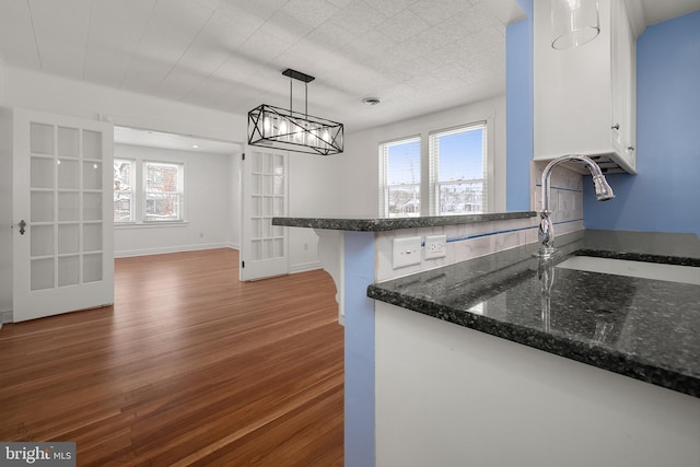 kitchen featuring white cabinetry, sink, dark wood-type flooring, kitchen peninsula, and decorative light fixtures