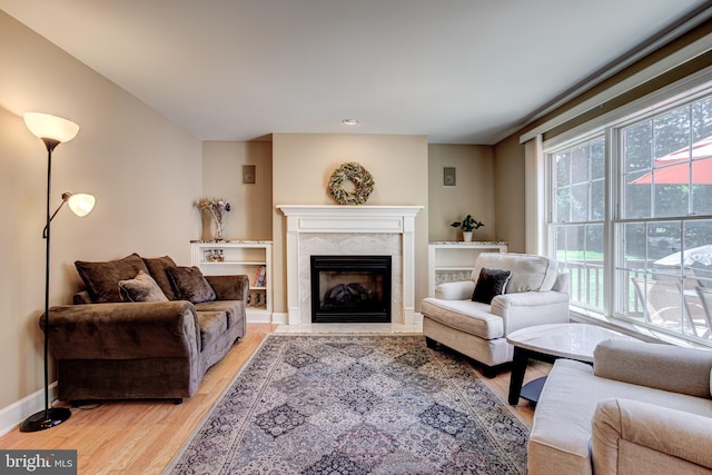 living area featuring light wood-type flooring, a fireplace, and baseboards