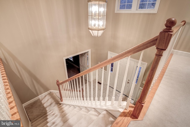 stairway featuring carpet floors, baseboards, and an inviting chandelier