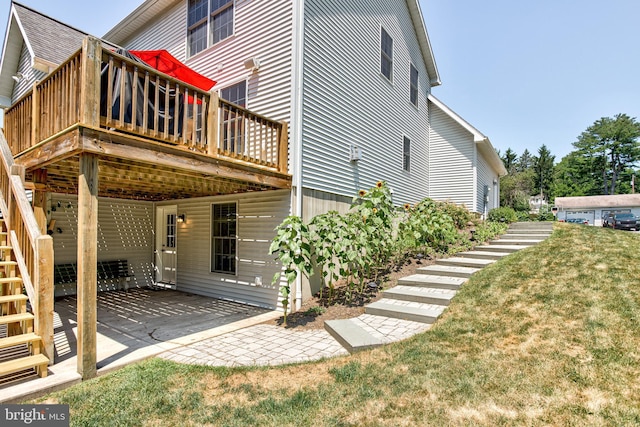 rear view of house featuring a patio, stairway, a wooden deck, and a lawn