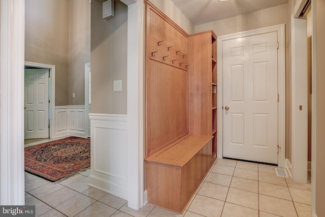 mudroom featuring a wainscoted wall, light tile patterned flooring, and a decorative wall