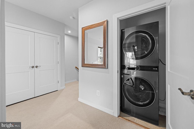 laundry room featuring light colored carpet and stacked washer and clothes dryer