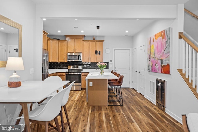 kitchen featuring sink, stainless steel appliances, hanging light fixtures, and dark wood-type flooring