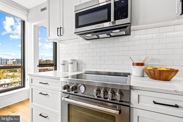 kitchen with appliances with stainless steel finishes, tasteful backsplash, and white cabinetry