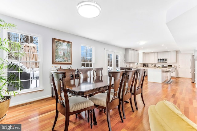 dining area featuring french doors and light wood-type flooring