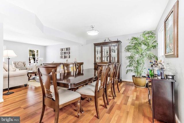 dining area featuring indoor bar and light hardwood / wood-style floors