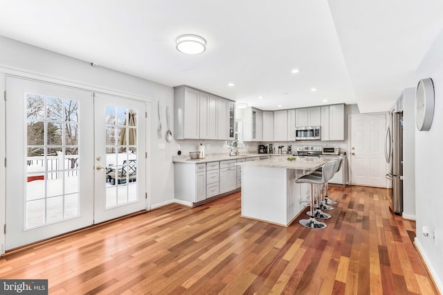 kitchen featuring light stone countertops, a kitchen breakfast bar, backsplash, a kitchen island, and appliances with stainless steel finishes