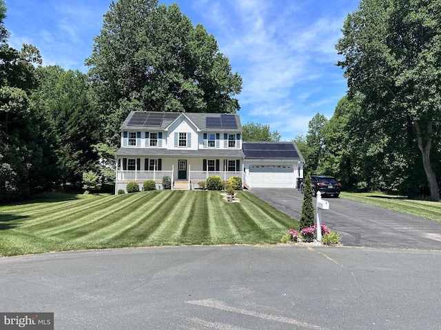 view of front facade featuring covered porch, solar panels, a garage, and a front lawn