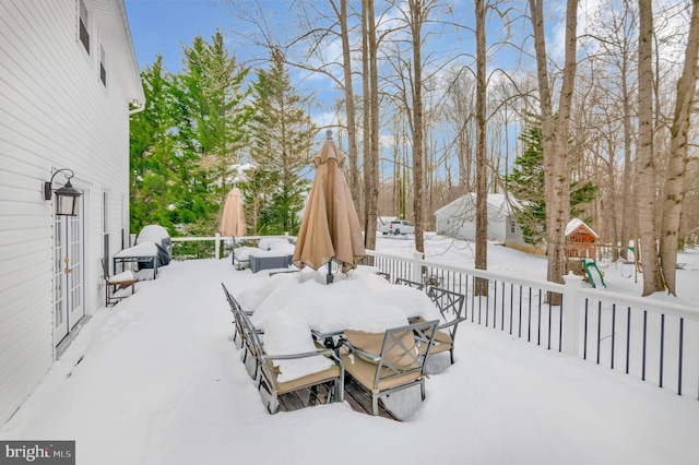 snow covered patio with a wooden deck