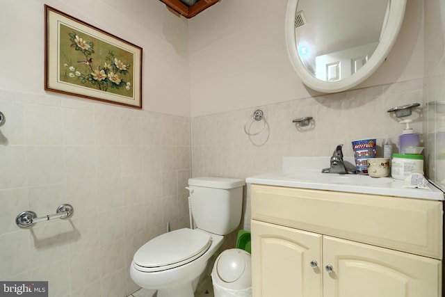 bathroom featuring vanity, toilet, and tile walls