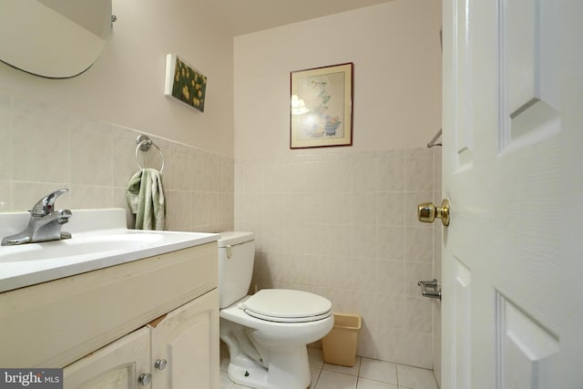 bathroom featuring toilet, vanity, tile patterned floors, and tile walls