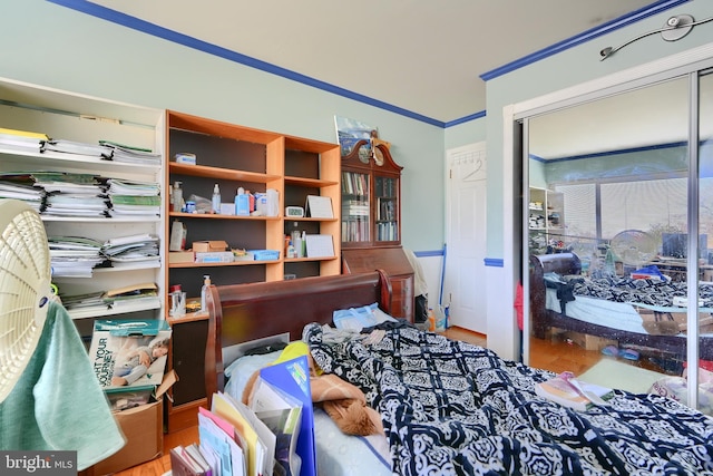 bedroom featuring wood-type flooring, crown molding, and a closet