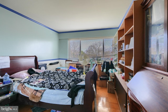 bedroom with crown molding and light parquet flooring