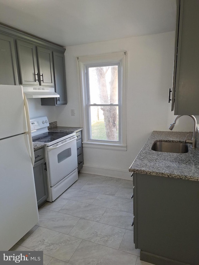 kitchen with stone counters, white appliances, and sink