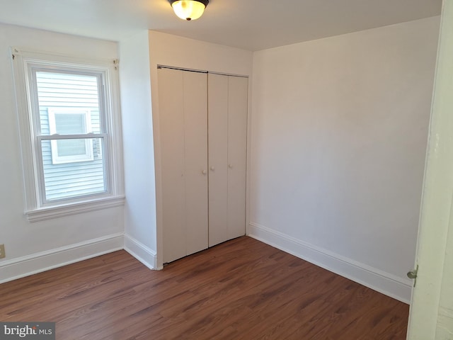 unfurnished bedroom with dark hardwood / wood-style flooring and a closet