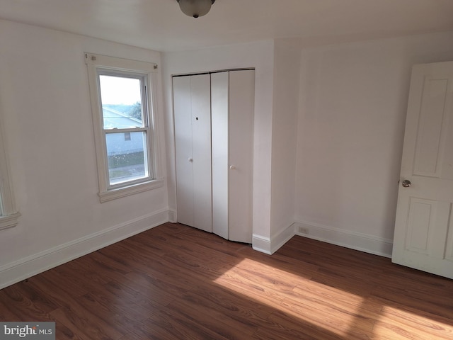 unfurnished bedroom featuring a closet and dark wood-type flooring