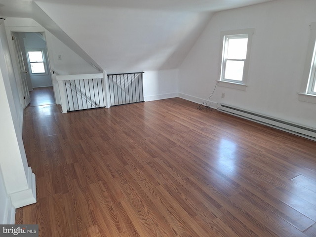 bonus room featuring baseboard heating, a wealth of natural light, dark wood-type flooring, and vaulted ceiling