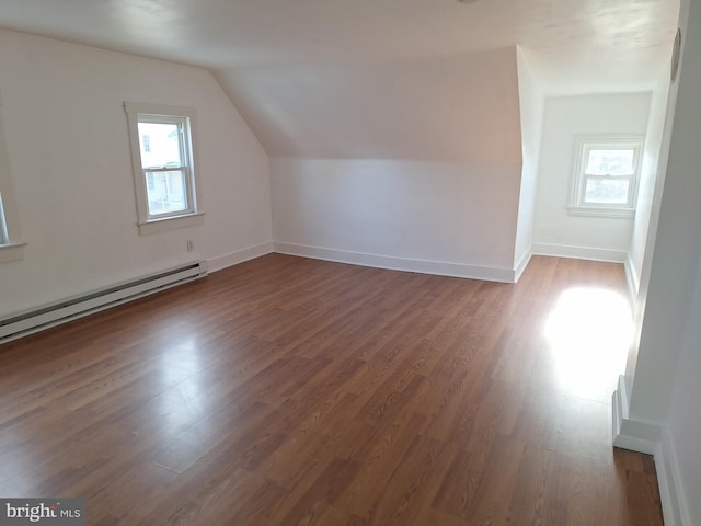 additional living space featuring dark hardwood / wood-style flooring, lofted ceiling, and a baseboard heating unit