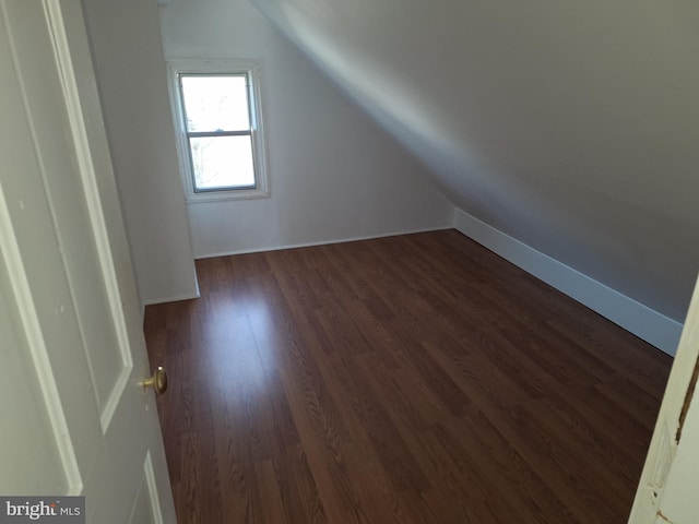 additional living space featuring dark wood-type flooring and vaulted ceiling