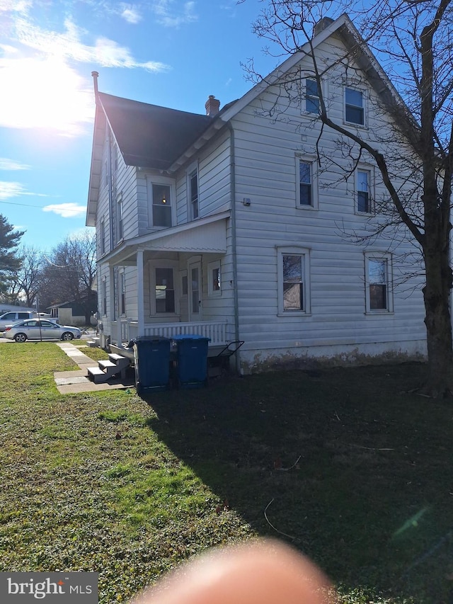 view of home's exterior with a lawn and covered porch