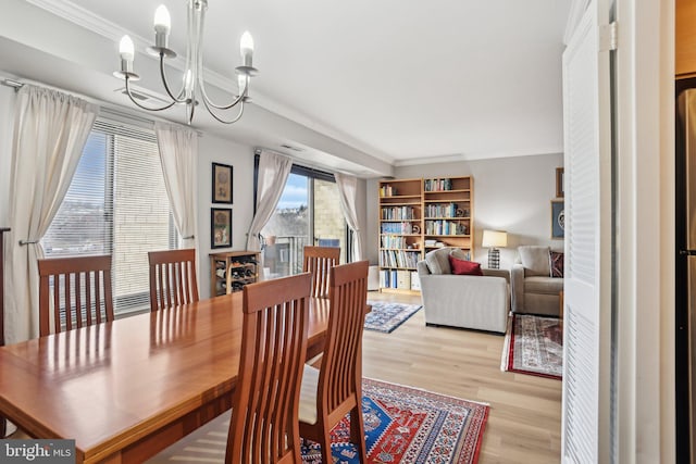 dining area with crown molding, a chandelier, and light wood-type flooring