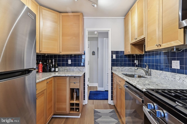 kitchen featuring stainless steel appliances, sink, light stone counters, and decorative backsplash