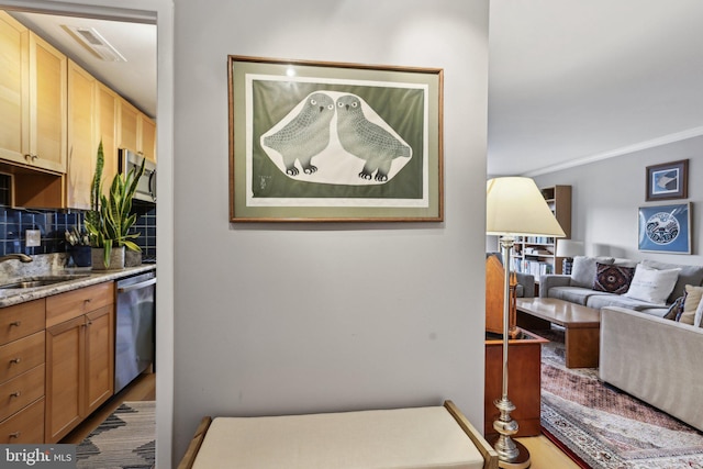 interior space featuring stainless steel dishwasher, sink, and decorative backsplash