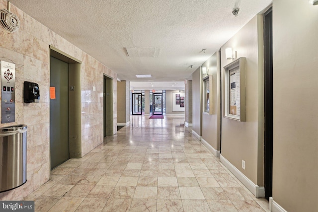 hall with elevator and a textured ceiling