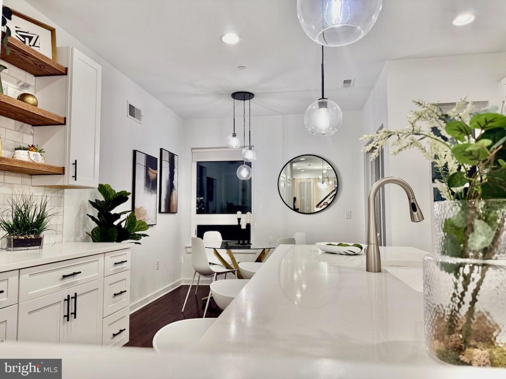 kitchen with dark hardwood / wood-style flooring, white cabinetry, backsplash, and hanging light fixtures