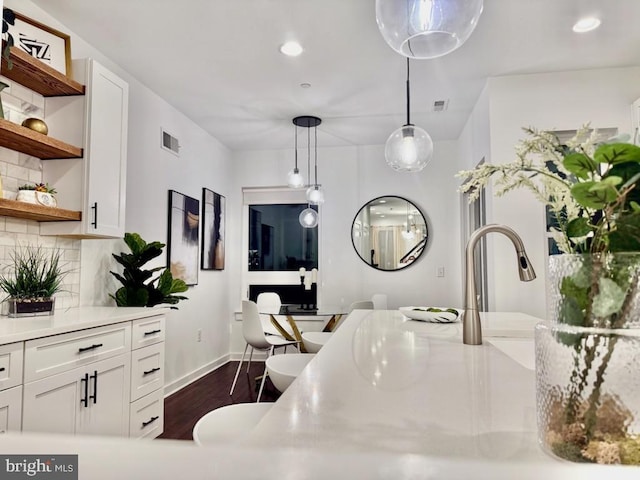 kitchen with dark hardwood / wood-style flooring, white cabinetry, backsplash, and hanging light fixtures