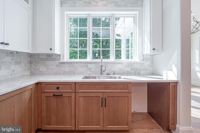 kitchen with white cabinets, backsplash, light hardwood / wood-style flooring, and sink