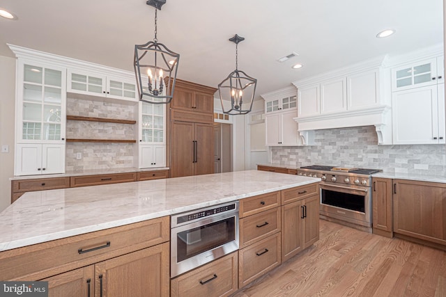 kitchen featuring white cabinetry, an inviting chandelier, light hardwood / wood-style flooring, pendant lighting, and appliances with stainless steel finishes