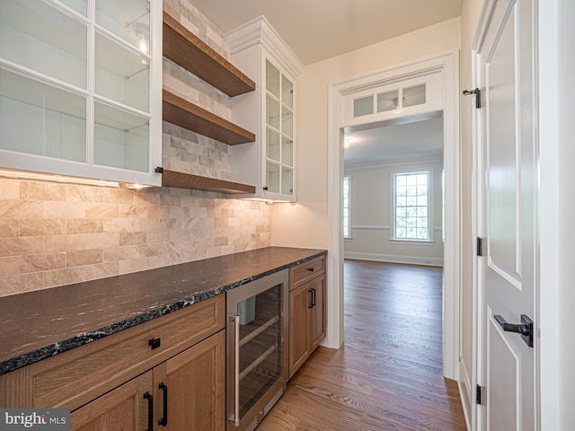 kitchen with light wood-type flooring, tasteful backsplash, wine cooler, and dark stone countertops