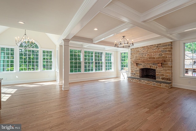 unfurnished living room with hardwood / wood-style flooring, a healthy amount of sunlight, a stone fireplace, and beam ceiling