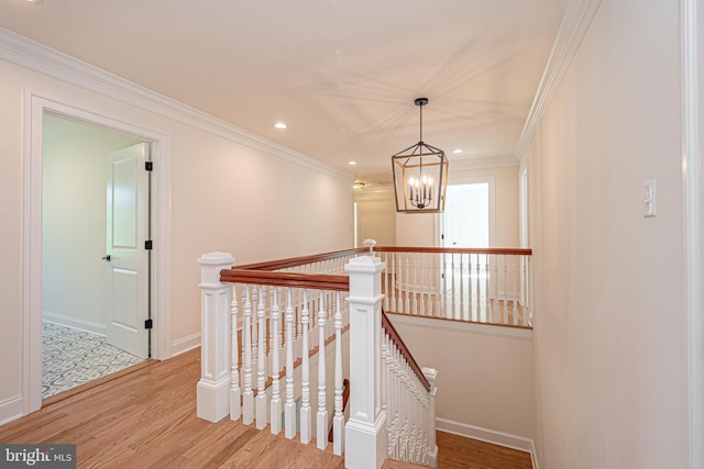 hallway featuring an inviting chandelier, ornamental molding, and light wood-type flooring