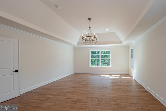 spare room featuring a notable chandelier, a raised ceiling, wood-type flooring, and crown molding