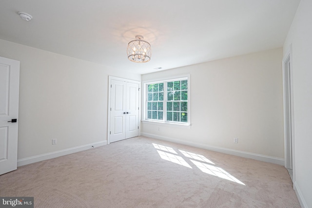 unfurnished bedroom with light carpet and a notable chandelier