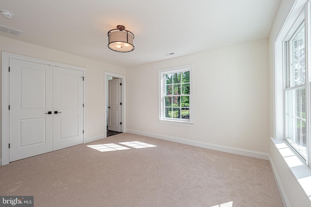 unfurnished bedroom featuring light carpet and a closet