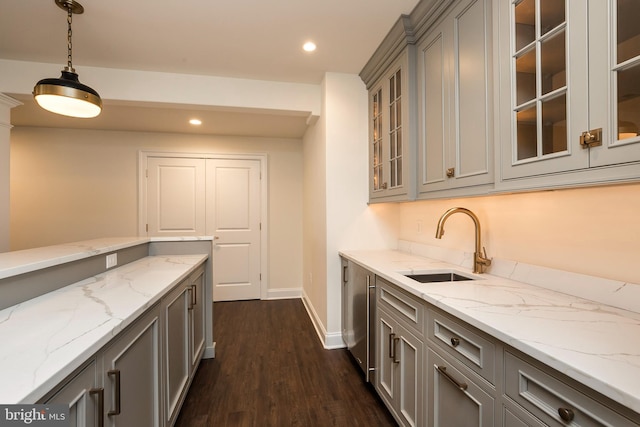 interior space featuring sink, dark hardwood / wood-style floors, gray cabinets, light stone countertops, and decorative light fixtures