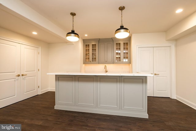 kitchen featuring sink, dark hardwood / wood-style floors, hanging light fixtures, and an island with sink