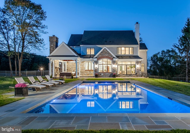 back house at dusk with a fenced in pool, a yard, and a patio