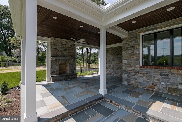 view of patio with an outdoor stone fireplace and ceiling fan