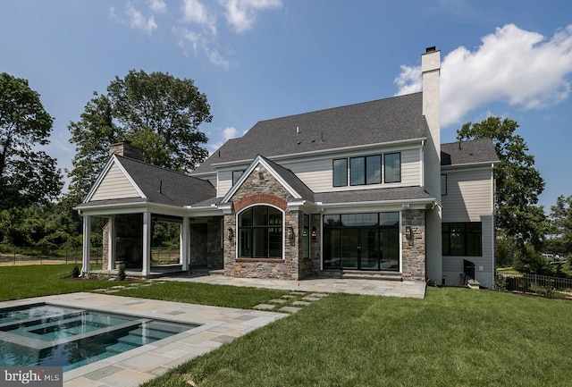 back of property featuring a lawn, a swimming pool with hot tub, and a patio