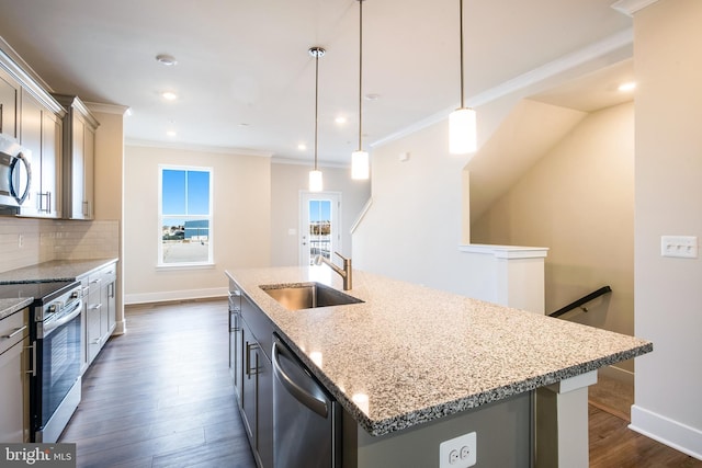 kitchen with sink, hanging light fixtures, light stone counters, an island with sink, and appliances with stainless steel finishes