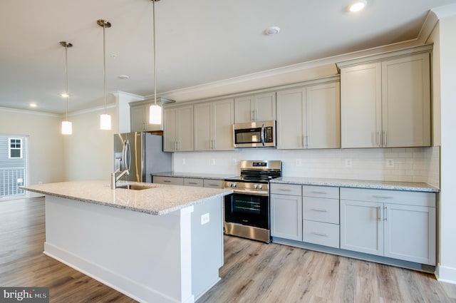 kitchen featuring pendant lighting, an island with sink, appliances with stainless steel finishes, tasteful backsplash, and light stone counters