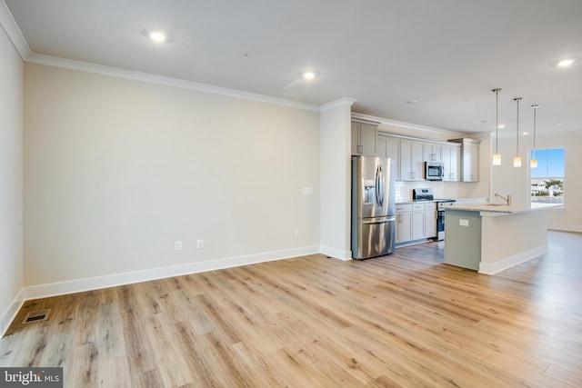 kitchen with sink, light stone counters, pendant lighting, appliances with stainless steel finishes, and ornamental molding