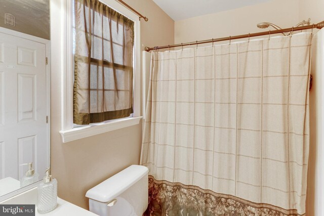 bathroom featuring a shower with shower curtain and toilet