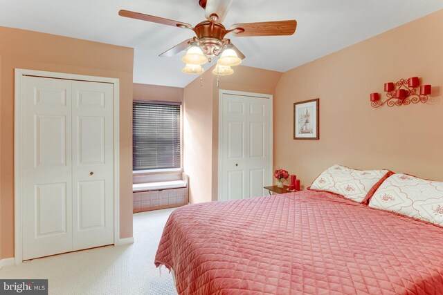 carpeted bedroom featuring ceiling fan and two closets