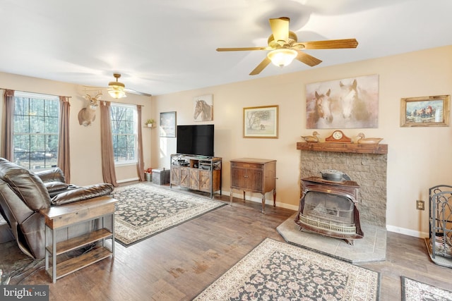 living room with a wood stove, ceiling fan, and hardwood / wood-style flooring